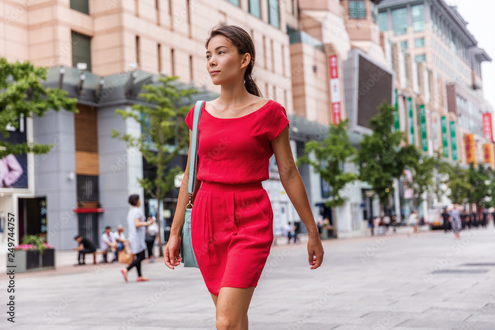 Asian young woman walking alone in city street relaxing enjoying modern Beijing travel lifestyle. Mixed race chinese caucasian girl commuting outside.