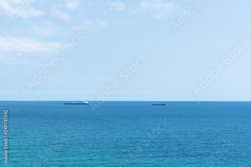 blue sea surface with small ships on the horizon © Aliaksei Luskin