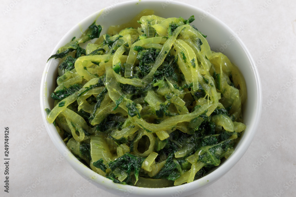 Stir fried spinach and onion. Concept of vegan food or garnish at least. White background. Stir fried spinach and onion. Concept of vegan food or garnish at least. White background.