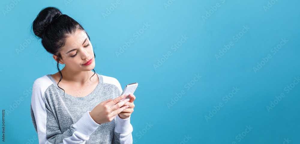 Young woman using her cellphone on a blue background Young woman using her cellphone on a blue background