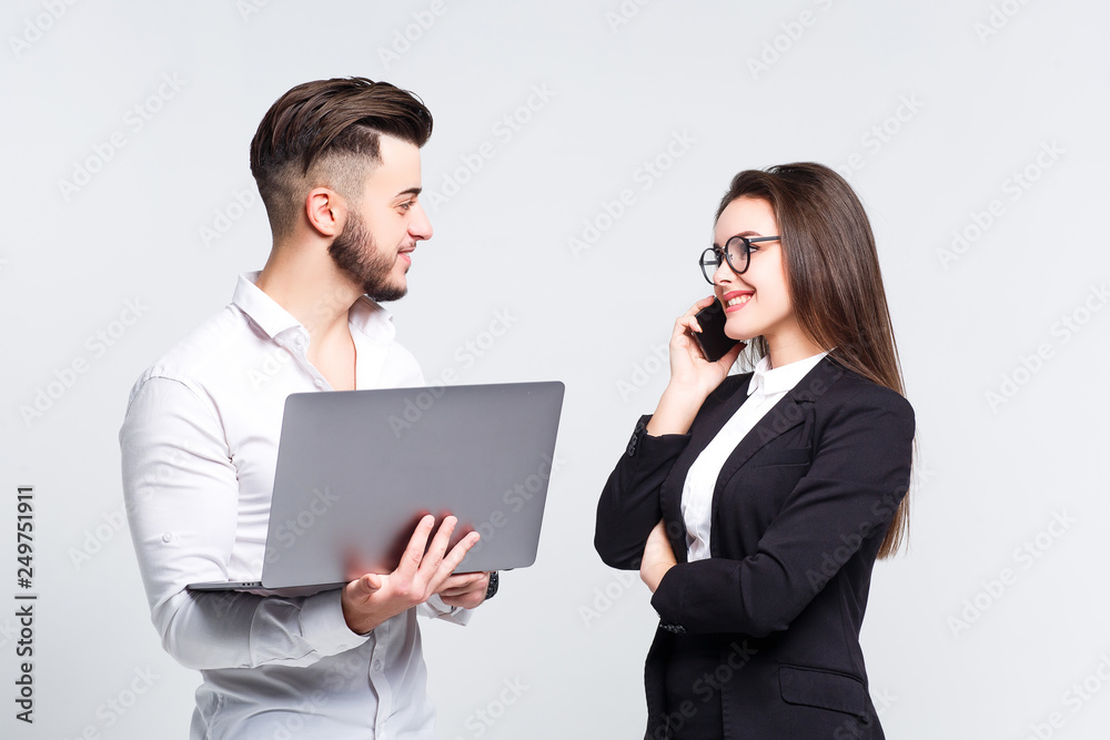 Pleased young business team working together at a laptop smiling, brunette girl speak by her phone. Pleased young business team working together at a laptop smiling, brunette girl speak by her phone.