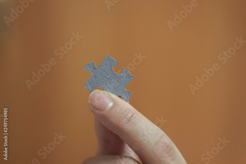 Holding two jigsaw pieces of a blank puzzle trying to fit together against blue sky background