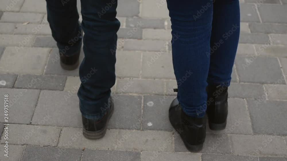 mother and baby legs in black boots walk down the sidewalk mother and baby legs in black boots walk down the sidewalk