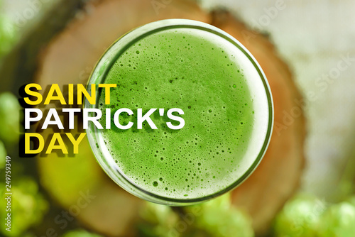 St. Patrick's day. Foam green beer on a wooden stand (top view). A glass of green beer close-up. Photo with text