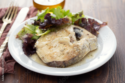 boiled fish with sauce and green salad on white plate