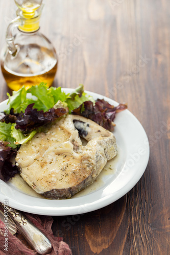 boiled fish with sauce and green salad on white plate