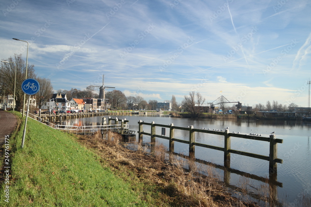 Oude Veerstal along the quay of river Hollandsche IJssel with windmill 't Slot in Gouda, the Netherlands