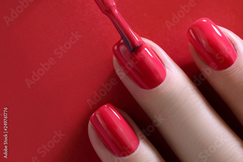 Valokuvatapetti Red Finger nail point isolated red background with nail polish