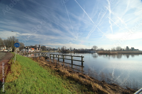 Oude Veerstal along the quay of river Hollandsche IJssel with windmill  t Slot in Gouda  the Netherlands