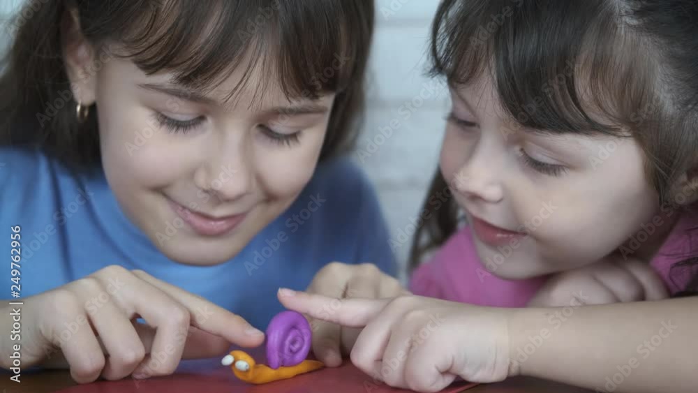 Children with plasticine snail. Little girls play with a snail made of plasticine.