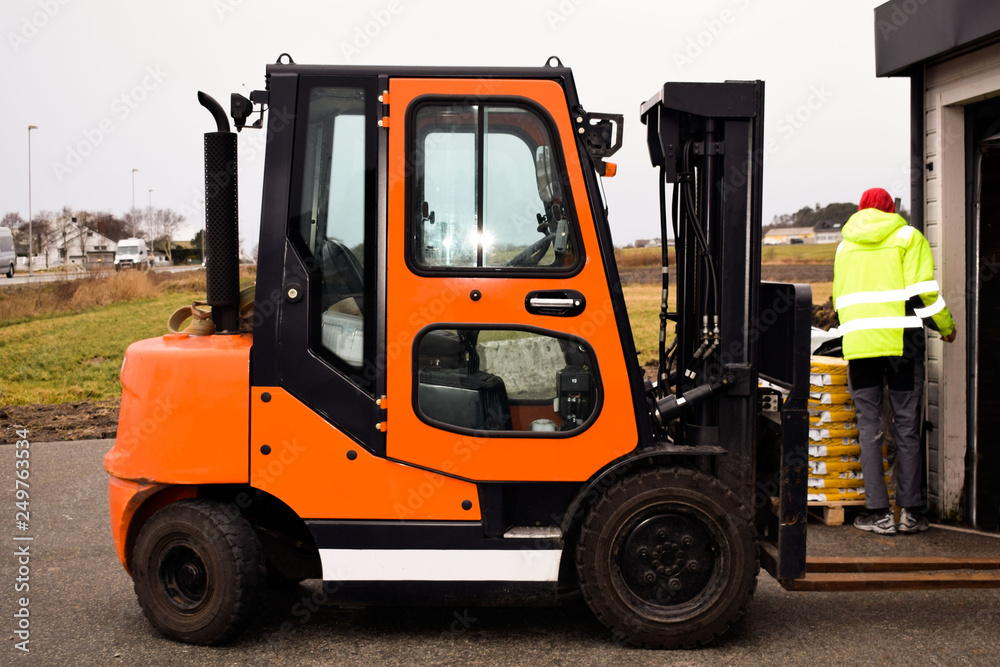 Reliable loader, forklift truck. A worker is ready to load pallets with a mini loader