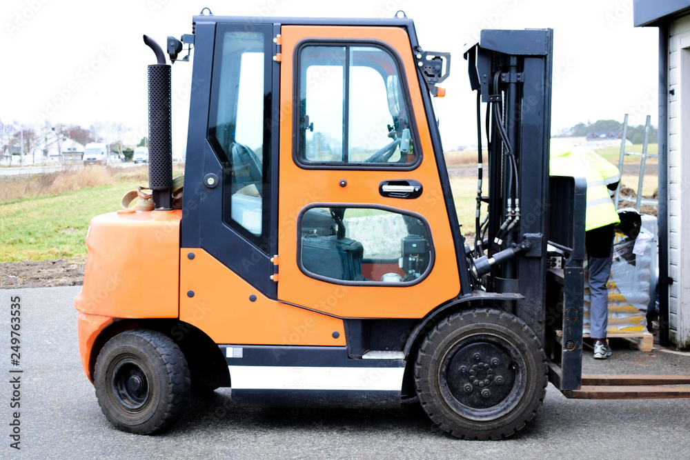 Reliable loader, forklift truck. A worker is ready to load pallets with a mini loader