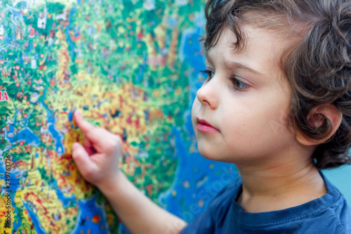 The curly-headed Child with interest looks at the blue world map