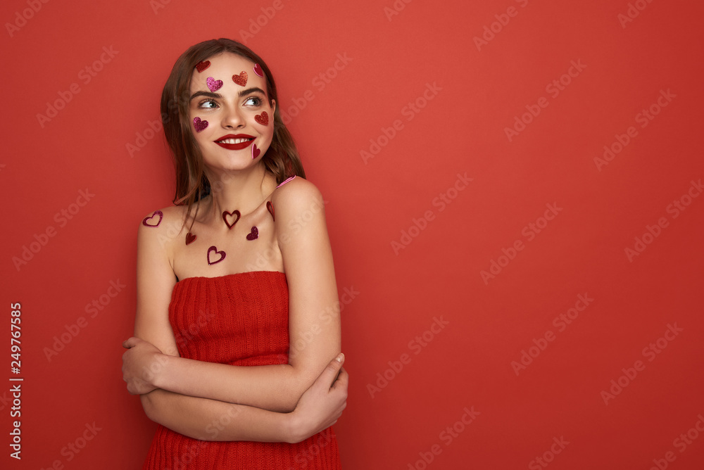 Beautiful Caucasian woman is decorated with red heart-shaped stickers on color background Beautiful Caucasian woman is decorated with red heart-shaped stickers on color background
