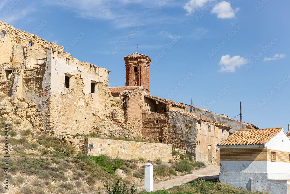 old rustic houses and the Santa Cruz parish church in Plou town, province of Teruel, Aragon, Spain