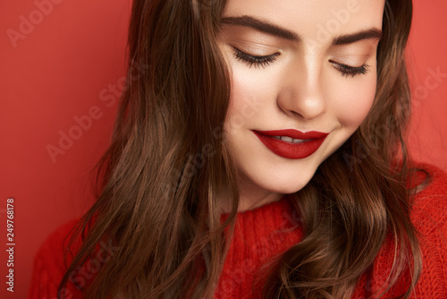 Cropped portrait of beautiful girl posing for camera on red background