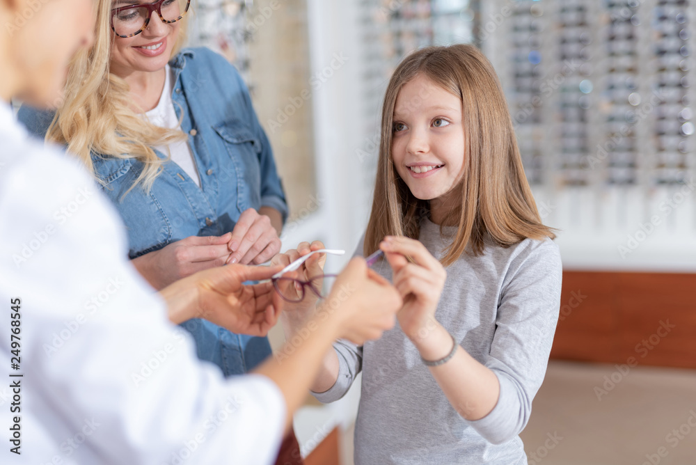 Fototapeta premium Positive nice girl trying up glasses for a better eyesight