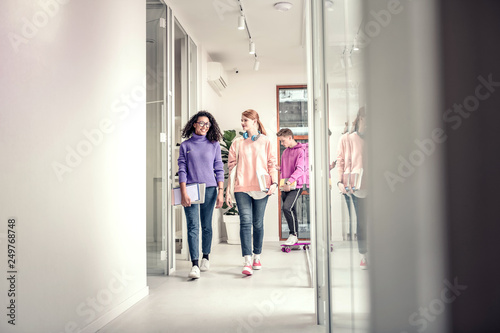 Two stylish students wearing jeans and sweatshirts walking to class