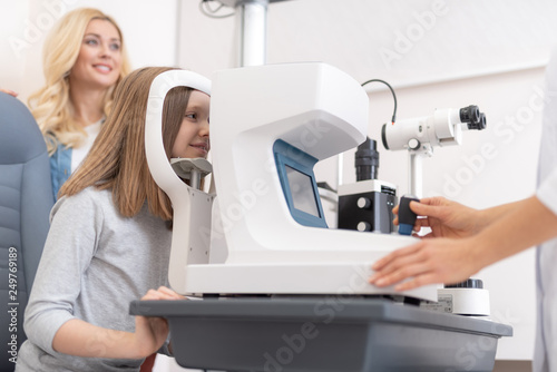 Ophthalmologist checking vision of little girl with autorefractor photo