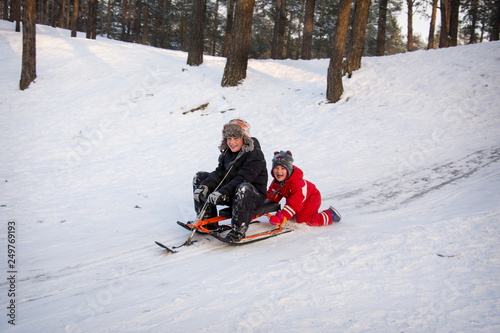 In winter, children ride a snow scooter from a hill.