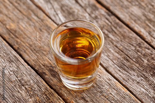 Shot glass of bourbon on weathered wood