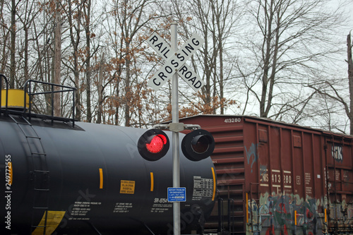 A Railroad Crossing warning sign with flashing lights and train cars