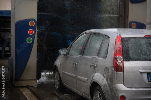 Car Covered by Active Foam During Car Washing entering the Brushes of a Washing Machine on Blur Background