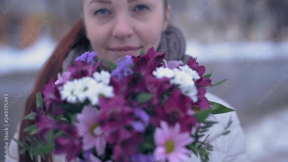 young lifestyle woman with flowers on a snowy street in early spring on a cloudy day and