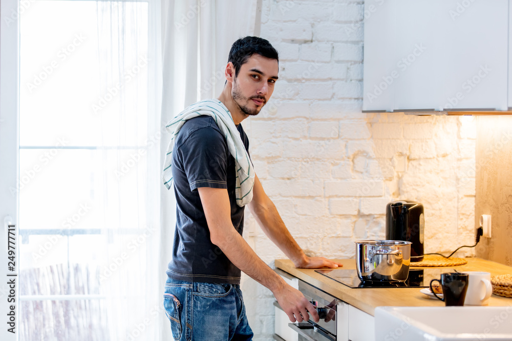Young man in black shirt cooking at kitchen in home. Young man in black shirt cooking at kitchen in home.