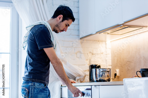 Young man in black shirt cooking at kitchen in home.