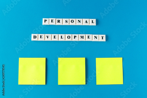 Personal development. Isolated text written on a blue background and notes paper. photo