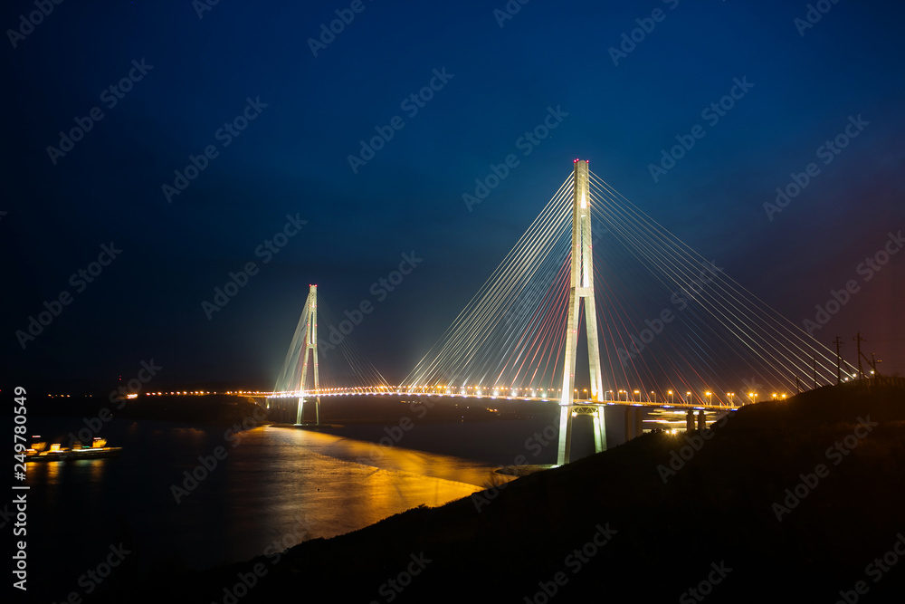 Amazing zooming out aerial view of the Russky Bridge, the world's longest cable-stayed bridge, and the Russky (Russian) Island in Peter the Great Gulf in the Sea of Japan. Sunrise. Vladivostok, Russia