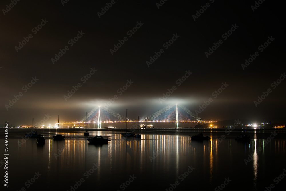 Amazing zooming out aerial view of the Russky Bridge, the world's longest cable-stayed bridge, and the Russky (Russian) Island in Peter the Great Gulf in the Sea of Japan. Sunrise. Vladivostok, Russia