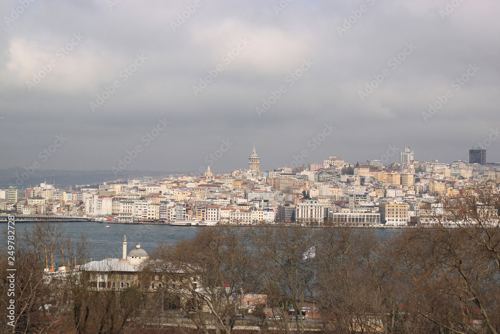 View of Istanbul through the Bosphorus and Golden Horn. Urban landscape with Galata Tower. Travel photography. Cloudy spring day.