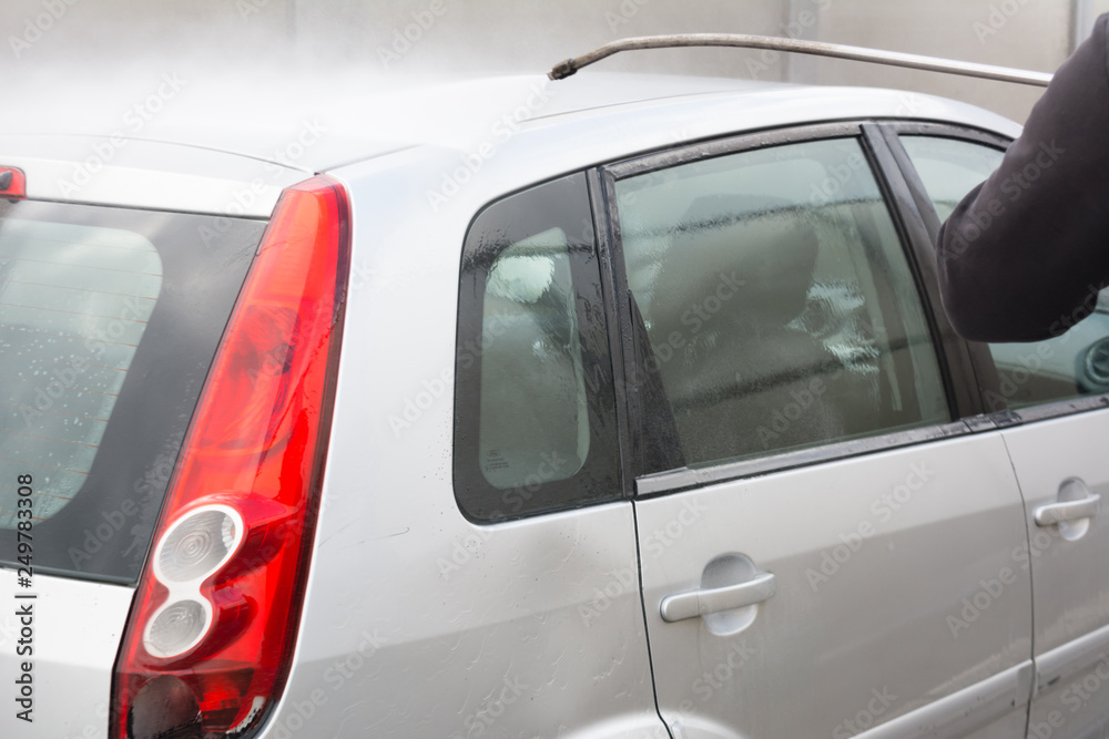 Man Using Water Pressure Machine to Wash a Car on Blurred Background Man Using Water Pressure Machine to Wash a Car on Blurred Background