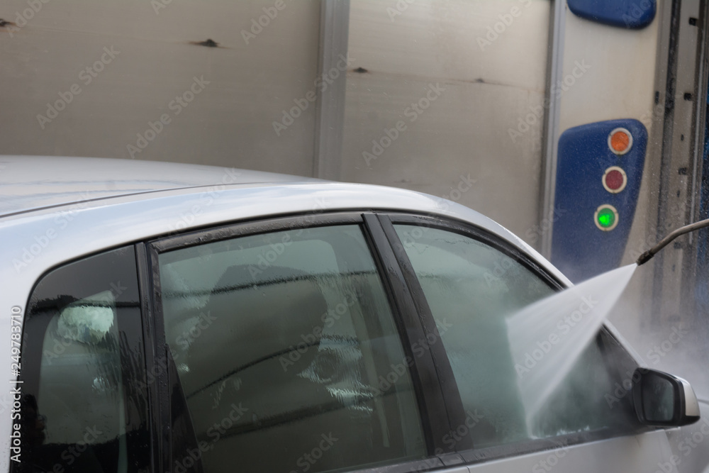 Man Using Water Pressure Machine to Wash a Car on Blurred Background