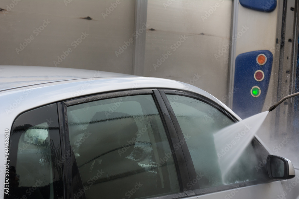 Man Using Water Pressure Machine to Wash a Car on Blurred Background Man Using Water Pressure Machine to Wash a Car on Blurred Background