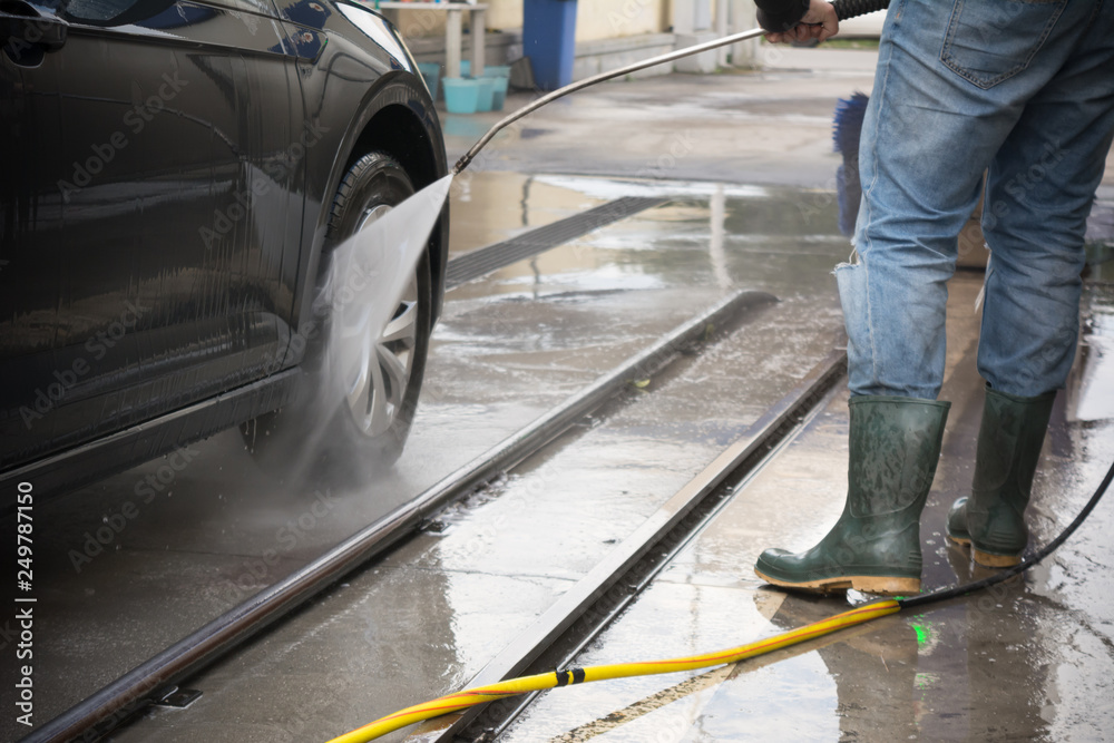 Man Using Water Pressure Machine to Wash a Car on Blurred Background Man Using Water Pressure Machine to Wash a Car on Blurred Background