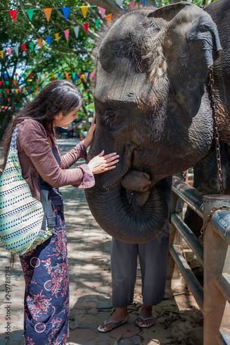 Teen girl tourist talking to baby elephant in Thailand photo