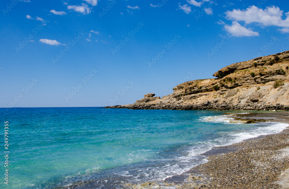 Secluded beach with clear blue water and small pebbles and sand, away from mass tourism in village of Chora Sfakion. Crete, Greece.