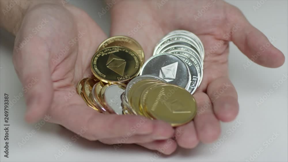 Male hands holding ethereum and bitcoin in silver and gold - eth, btc coin