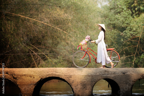 Foto woman with Vietnam culture traditional dress, Ao dai and bicycle on the bridge