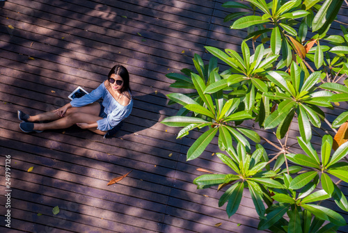 The girl sat on the tablet while sitting in the garden. photo