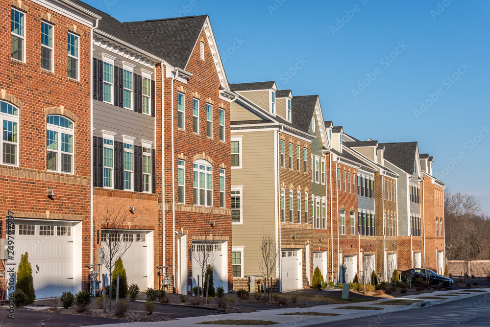 Typical American town house, town home neighborhood with colorful real estate houses at a new construction East Coast Maryland location with blue sky