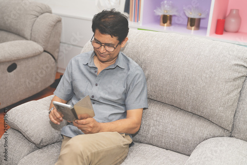 Senior man sit on sofa with looking smartphone in living room at home