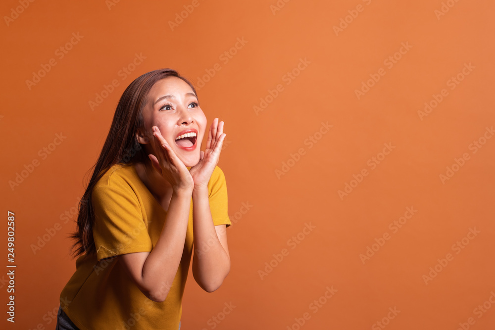 Young Asian woman portrait over orange background announce shot, smile happy studio shot Young Asian woman portrait over orange background announce shot, smile happy studio shot