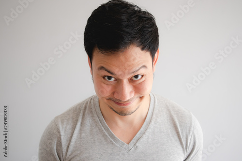 Funny tricky awkward smirk face of man in grey t-shirt.