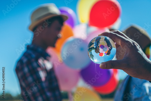 Reflection of couples with balloons in a glass ball in a handle