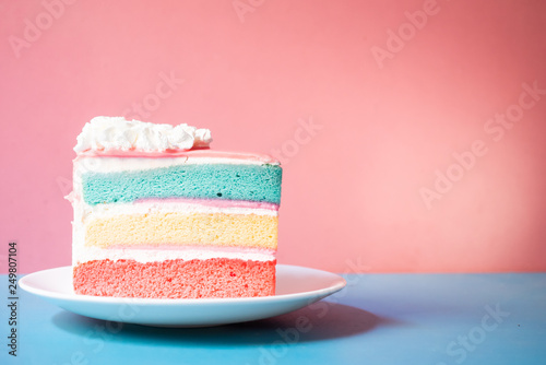 layer rainbow cake with spoon wooden on pink background