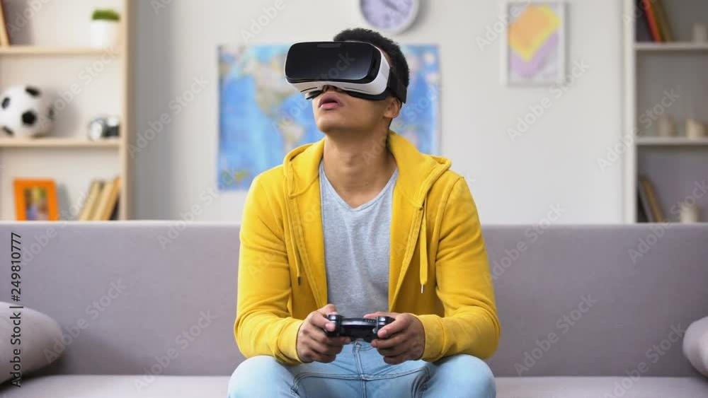 Afro-American teenage boy playing video game in VR headset, modern technologies Afro-American teenage boy playing video game in VR headset, modern technologies